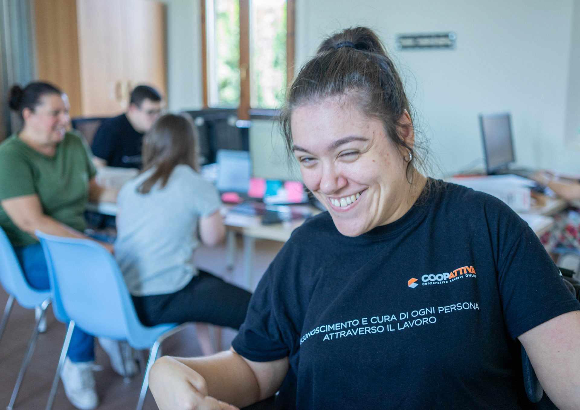 Donna sorridente con maglia coopattiva nel laboratorio digital Lab
