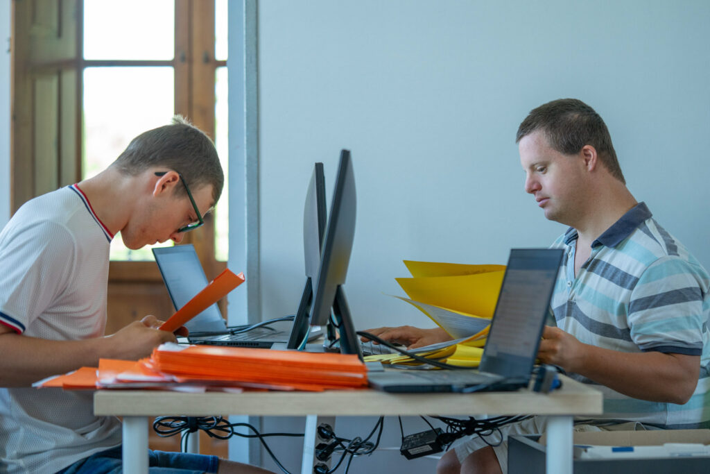 Due uomini mentre lavorano nel digital lab coopattiva, davanti a monitor nella loro postazione