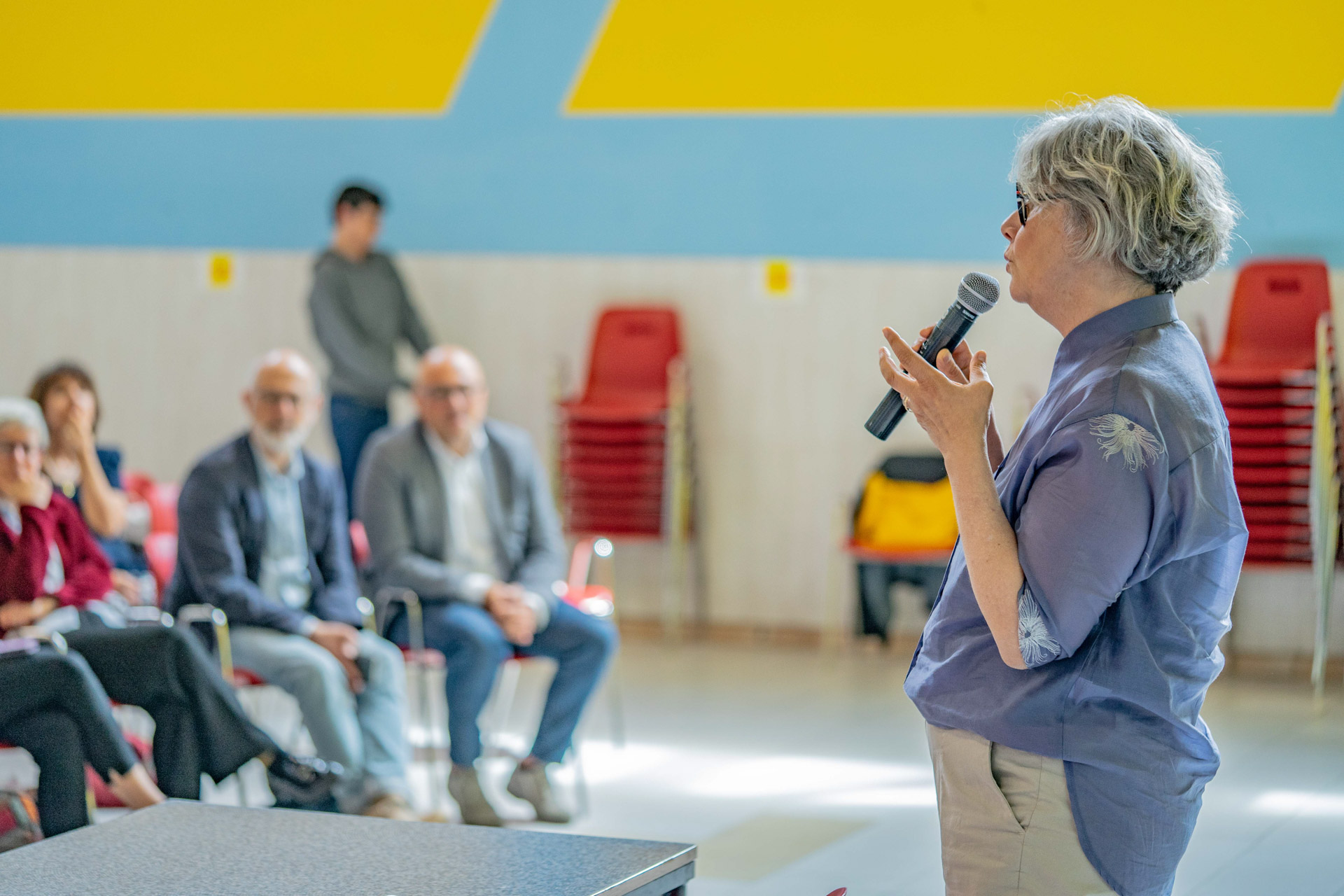 Primo pianop di una donna durante uno formazione team coopattiva, davanti ad una platea.