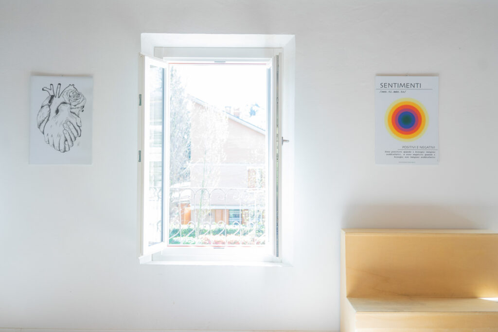 Foto di un ufficio coopattiva per mediazione conflitti. Sulla sinistra c'è un quadro con un cuore a forma di mano, al centro una finestra e sulla destra un quadro con una grafica dal titolo Sentimenti.