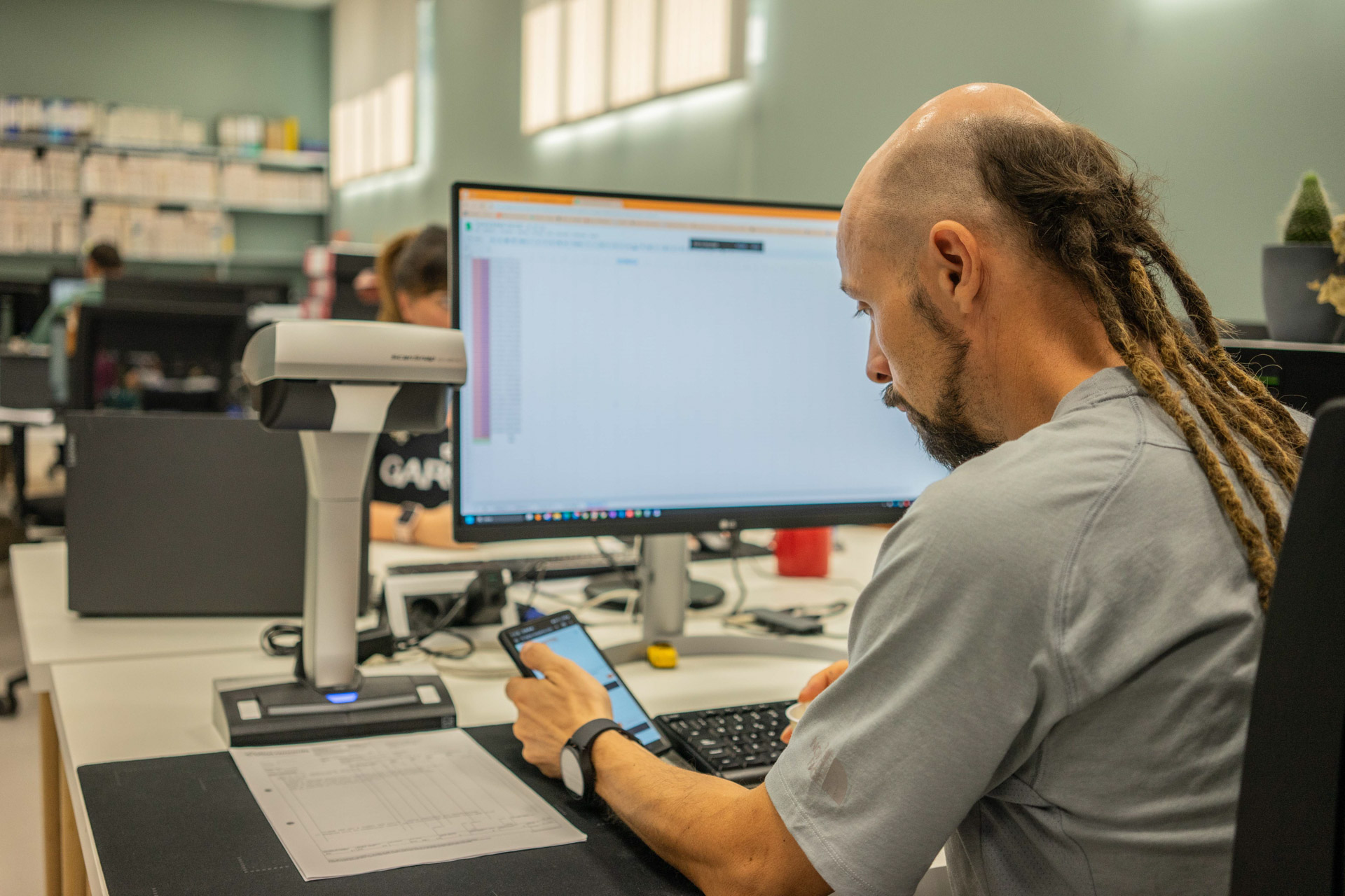Uomo davanti al computer mentre sta digitalizzando documenti a coopattiva servizio puntilinea