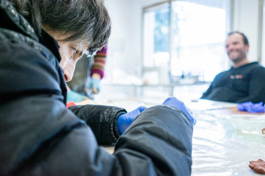 Donna intenta a modellare argilla durante il laboratorio ceramico di coopattiva