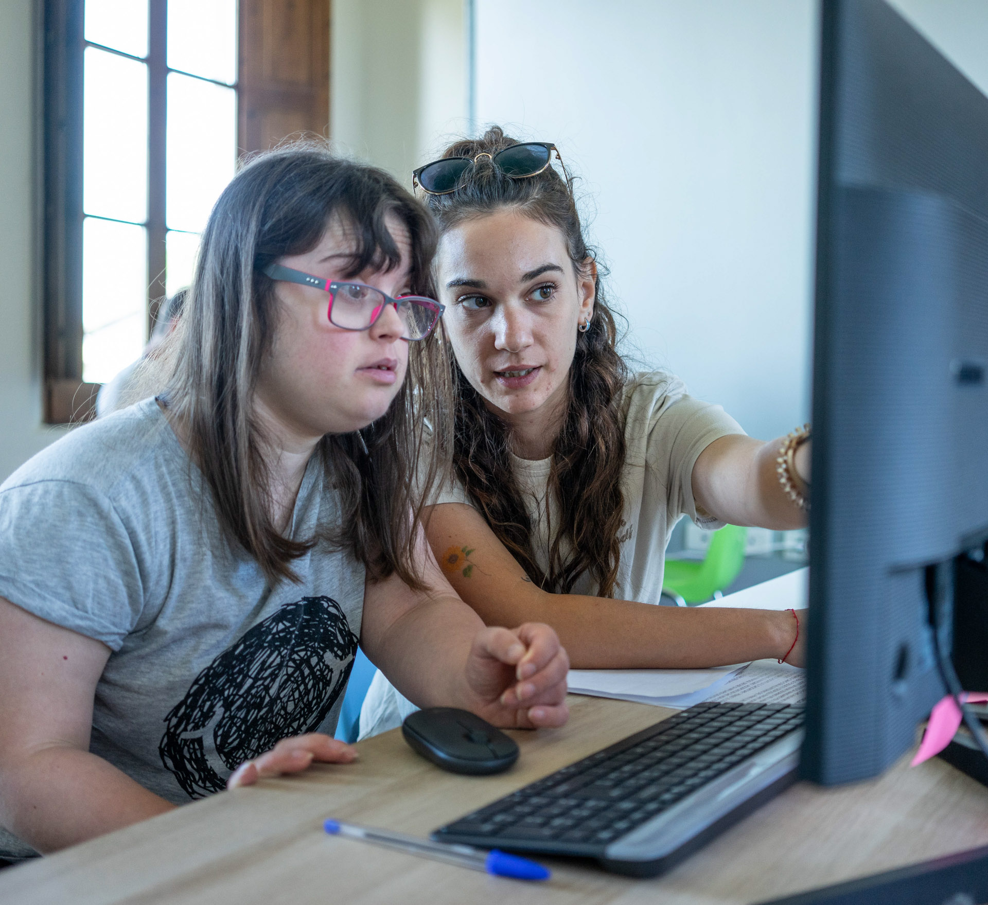 Due ragazze che ripassano davanti ad un monitor durante un intervento coopattiva per le scuole