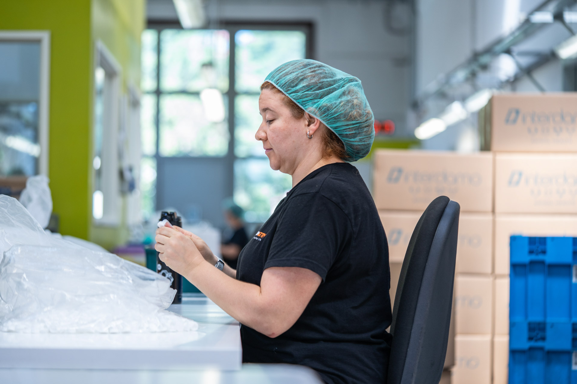 Donna con cuffia per capelli che lavora nel laboratorio di coopattiva.